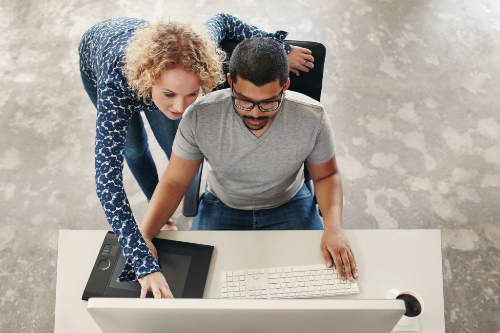 A man and woman looking at a computer screen.