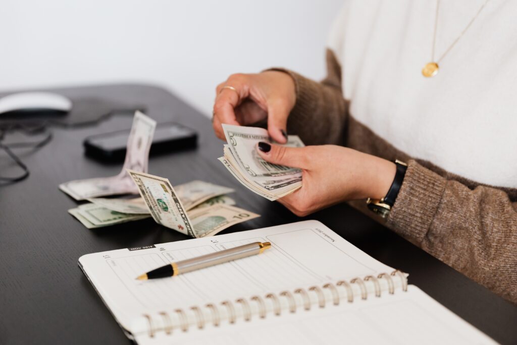 A person is counting money on top of a table.