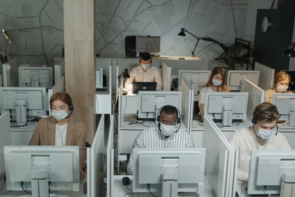 A group of people wearing masks in an office.